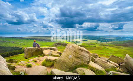 Ein Rambler auf Higger Tor in Derbyshire Peak District mit Carl Wark im Mittelgrund. Stockfoto