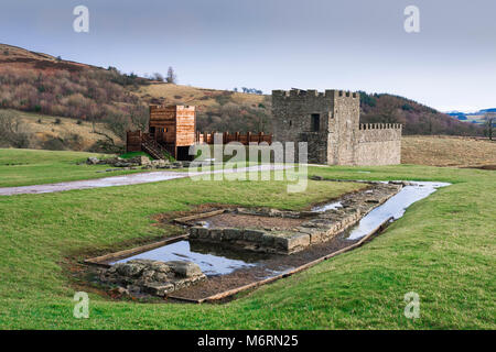Roman fort: Vindolanda, Blick auf die rekonstruierten Turm Abschnitt der Hadrian's Wall mit ausgegraben Wassertank Notunterstände im, Northumberland, England, Großbritannien Stockfoto