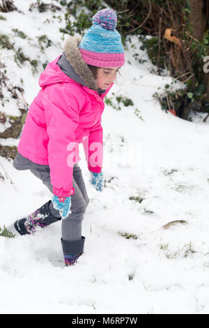 Süße kleine Mädchen im Schnee spielen. Hübsches weibliches Kind tragen rosa Mantel spielt in schneereichen Winter Wetter Stockfoto