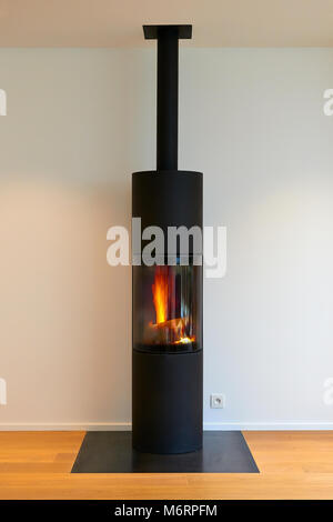 Modernes Metall Kamin mit Flamme gegen weiße Wand Stockfoto