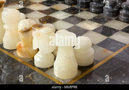 Schwarze und weiße Marmor Schachfiguren auf einem Schachbrett Stockfoto