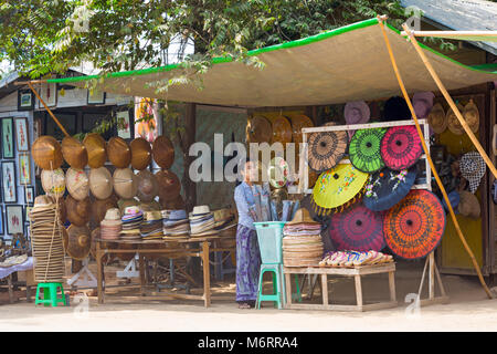 Frau Verkauf von traditionellen konischen Hüte und Sonnenschirmen auf Abschaltdruck am Mingun, Myanmar (Burma), Asien im Februar Stockfoto