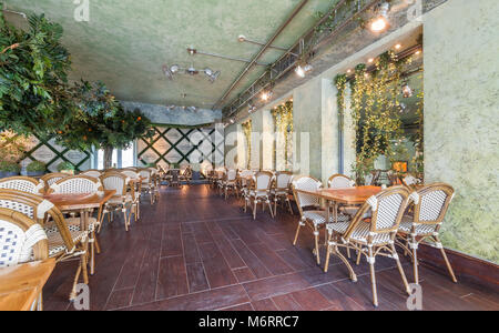 Moskau - Juli 2014: Chain Home Cooking Restaurant "GRABLI". Der Innenraum des Konzept der Gartenkunst Stil. Holztische mit Korbstühlen Stockfoto