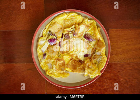 Omelette, gemischt mit roten Zwiebeln und Fisch Kugel hausgemachtes auf der Platte mit Holz- Hintergrund - Ansicht von oben Stockfoto