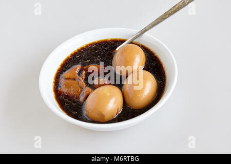 Die hart gekochten Eier und Schweinefleisch und Tofu im süßen braunen Soße Soße auf den weißen Hintergrund (Thai namens 'sKai-Pa-Lo) - Ansicht von oben Stockfoto