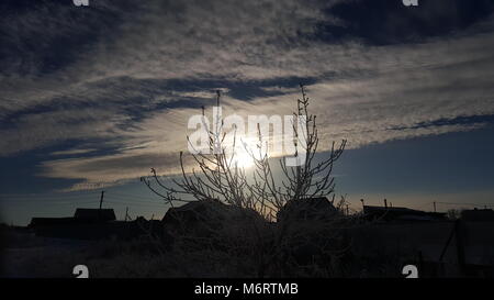 Wolken und ein Stück blauer Himmel über den Dächern der Häuser. Silhouette und Haltestangen auf dem Dach Häuser sonnenuntergang himmel Gold Farbe am Abend Stockfoto