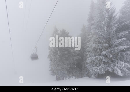 Leere Seilbahn in einem Skigebiet in den Schweizer Alpen im tiefen Winter auf einem sehr nebligen Tag bei schlechtem Wetter Stockfoto