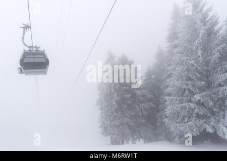 Leere Seilbahn in einem Skigebiet in den Schweizer Alpen im tiefen Winter auf einem sehr nebligen Tag bei schlechtem Wetter Stockfoto