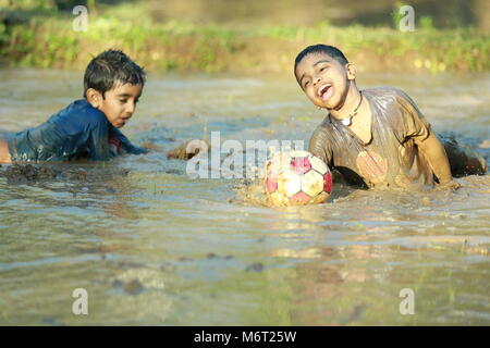 Glückliche Kindheit, Schlamm Spielen, Fußball, Spaß mit Natur, Kindheit genießen, Kinder Fußball, Erinnerungen, Spaß, Kinder Zyklus, Baum mit Junge, Spiel Stockfoto