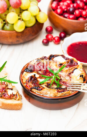 Backen Camembert mit Preiselbeersoße und Rosmarin serviert mit geröstetem Brot und Trauben Stockfoto