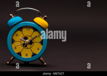 Der Wecker auf schwarzem Hintergrund. Farbige Stockfoto