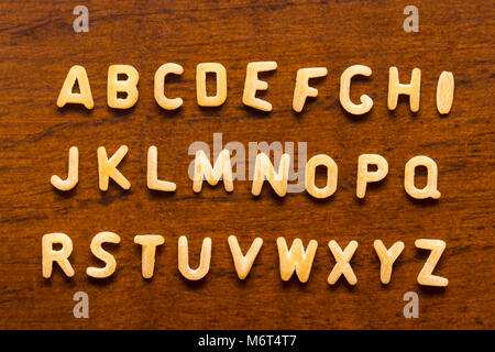 Alphabet aus makkaroni Buchstaben auf Holz Hintergrund isoliert. Stockfoto