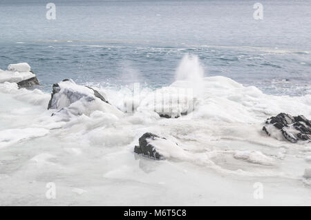 Das Sea Shore ist das eis-kalte und verschneite Küste und starke Wellen, Spritzer in den Himmel. Fernost Meer Landschaft von Russland Stockfoto