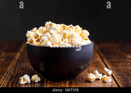 Eine Schüssel mit Popcorn auf einer hölzernen Hintergrund. Stockfoto