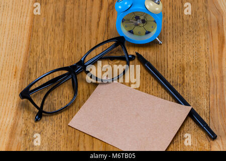 Leeres Blatt Papier mit Brillen, Wecker und Stift auf Holztisch. Stockfoto