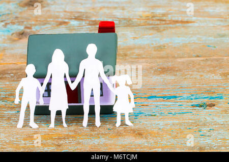 Papier Silhouette der Familie und dem Haus auf hölzernen Schreibtisch. Versicherungen Konzept. Stockfoto
