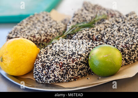 Gekochte Steaks von Thunfisch in Schwarz und Weiß Sesam auf einem Teller mit Limette und Zitrone Stockfoto