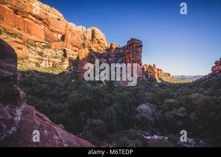 Atemberaubende Aussicht auf Fay Canyon von oben die Baumkronen mit Patches von Schnee auf dem Boden und majestätischen Blick auf Bell Rock und den Courthouse Butte in der Dis Stockfoto