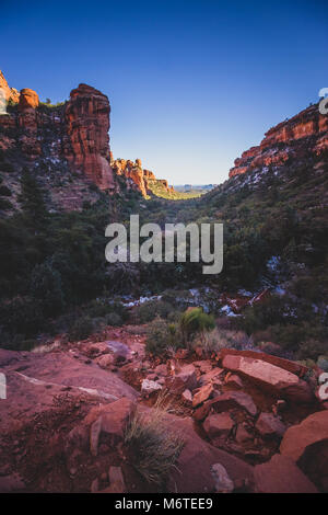 Atemberaubende Aussicht auf Fay Canyon von oben die Baumkronen mit Patches von Schnee auf dem Boden und majestätischen Blick auf Bell Rock und den Courthouse Butte in der Dis Stockfoto