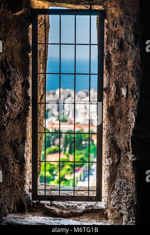 Blick aus einer Gefängniszelle vergitterten Fenster in ein altes Gefängnis, das in moderne Stadt Landschaft ruinieren. Hinter Gittern Fenster zur Außenwelt. Stockfoto