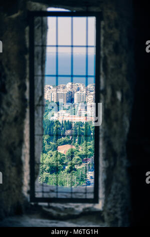 Blick aus einer Gefängniszelle vergitterten Fenster in ein altes Gefängnis, das in moderne Stadt Landschaft ruinieren. Hinter Gittern Fenster zur Außenwelt. Stockfoto