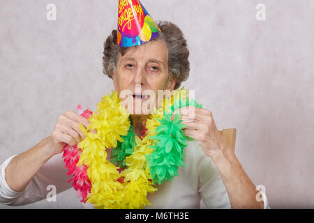 Ältere Frau von 80 Jahre alten ist bereit für die Geburtstagsparty. Auf dem Konus Übersetzung aus dem Russischen: "Happy Birthday". Stockfoto
