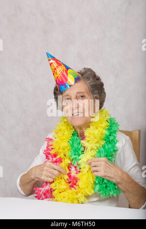 Ältere Frau von 80 Jahre alten ist bereit für die Geburtstagsparty. Auf dem Konus Übersetzung aus dem Russischen: "Happy Birthday". Stockfoto
