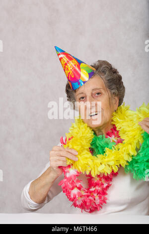 Ältere Frau von 80 Jahre alten ist bereit für die Geburtstagsparty. Auf dem Konus Übersetzung aus dem Russischen: "Happy Birthday". Stockfoto