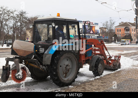 Jewpatoria, Krim, Russland - 28. Februar 2018: Traktor löscht Schnee am Theaterplatz in Jewpatoria, Krim Stockfoto