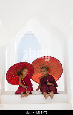 Junge Novizin buddhistische Mönche holding Sonnenschirme am Myatheindan Pagode (auch als Hsinbyume Pagode bekannt), Mingun, Myanmar (Burma), Asien im Februar Stockfoto