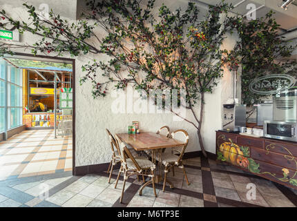 Moskau - Juli 2014: Chain Home Cooking Restaurant "GRABLI". Separate Tabelle im Schatten eines künstlichen Baum Stockfoto