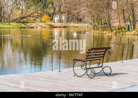 Eines Fischers Ort am Ufer des Sees an einem klaren, sonnigen Tag im Frühling. Plätze für Angelruten, Angeln Sitz, hölzernen Pier. Das Konzept der o Stockfoto