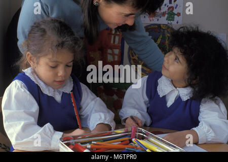 Zwei kleine Mädchen mit Lehrer oder Eltern im Klassenzimmer Stockfoto