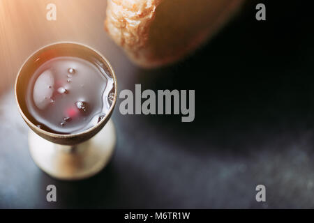 Die heilige Kommunion auf Holztisch auf Kirche. Die heilige Kommunion. Schale aus Glas mit Rotwein, Brot. Das Fronleichnamsfest Konzept. Stockfoto