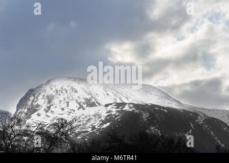 Vom Westen aus gesehen, die Sonne bricht durch stürmische Wolken Schnee auf dem Gipfel des Ben Nevis (in den Highlands von Schottland), der höchste Berg in der U Stockfoto