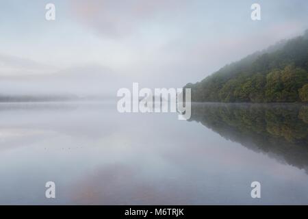 Ein sehr nebligen herbstlichen Morgen auf Loch Achray. Ich nahm diese so wie die Sonne die Wolken rosa aber der Nebel verbreitet die Szene sehr gut. Stockfoto