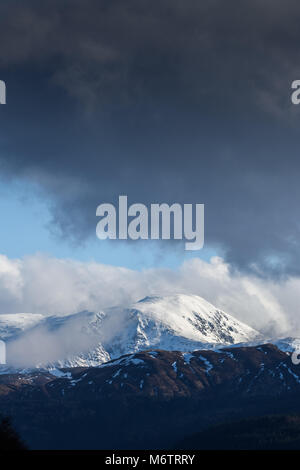 Von Süden gesehen - West, die Sonne bricht durch stürmische Wolken Schnee auf dem Gipfel des Ben Nevis (in den Highlands von Schottland), der höchste Berg Stockfoto