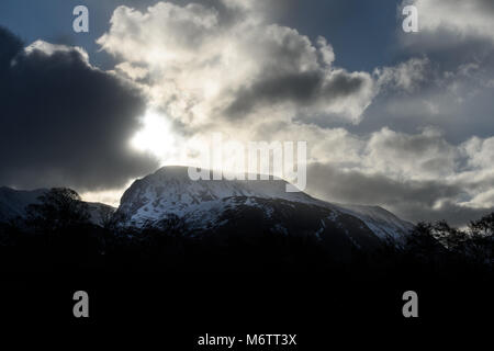 Vom Westen aus gesehen, die Sonne bricht durch stürmische Wolken Schnee auf dem Gipfel des Ben Nevis (in den Highlands von Schottland), der höchste Berg in der U Stockfoto