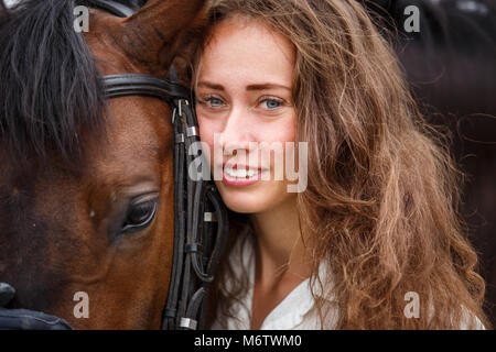 Junge happy rider Frau mit ihrem Bay Horse. Portrait von lächelnden Mädchen mit ihrem Hengst im Fahrerlager auf Sommer Tag Stockfoto