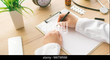 Ärztin Notizen, medizinische Geschichte des Patienten oder Medizin Rezept auf Zwischenablage Papier während der medizinischen Untersuchung im Krankenhaus Büro Stockfoto