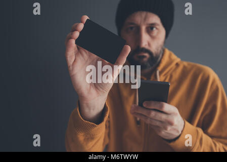 Legerer Mann zeigt leere Mock up Kreditkarte als Kopie Raum und hält Mobiltelefon in der anderen Hand für online Zahlung und Electronic Banking Stockfoto
