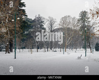 Leerer Park im Schnee mit Holzbänken abgedeckt. Stockfoto