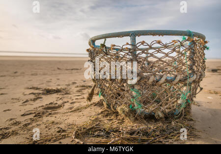 Eine Flut hinterlässt Detritus einschließlich beschädigter Lobster Trap auf Cefn Sidan. Carmarthenshire, West Wales. UK. Stockfoto