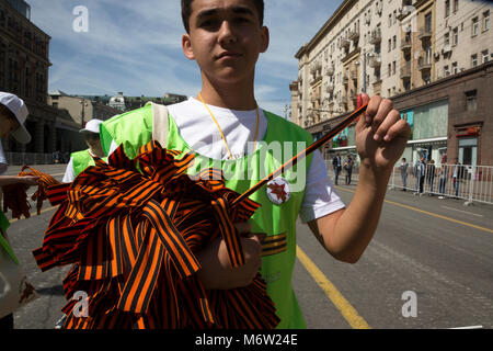 Ein freiwilliger Hände St George (Georgiyevskaya) Bänder für die öffentliche an der Tverskaya Straße während der Feier Tag des Sieges in Moskau, Russland Stockfoto