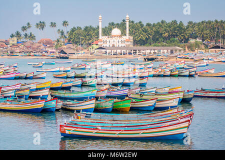 Bunte bemalte Fischerboote mit Moschee im Hintergrund im Vizhinjam Fischerdorf Port, Kerala, Indien Stockfoto