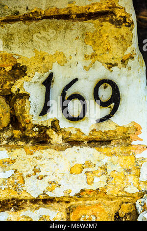 Haus Nummer 169 in Gusseisen Nummerierung auf einen gelben Stein Wand. Stockfoto