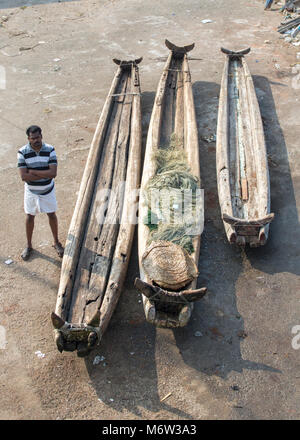 Mann neben traditionellen Fischerbooten im Fischerdorf Vizhinjam, Kerala, Indien Stockfoto