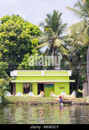 Frau wäscht Kleidung im Fluss vor dem Haus in Kerala Backwaters bei Alappuzha (Alleppey) Stockfoto