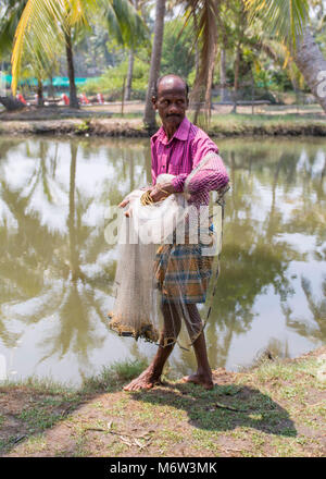 Indischer Mann, der Fischernetz am Wasser hält in Kumbalangi Village, Cochin, Kochi, Indien Stockfoto