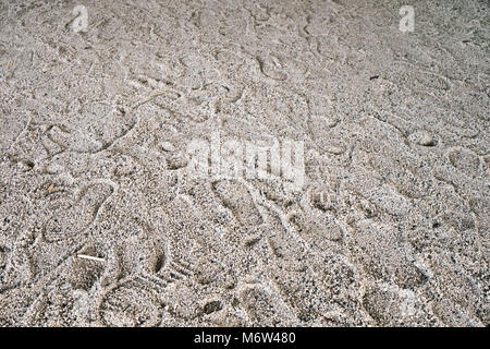 Verschiedene Menschen Fußabdrücke auf trockenem Sand, Hintergrund. Selektiver Fokus Stockfoto